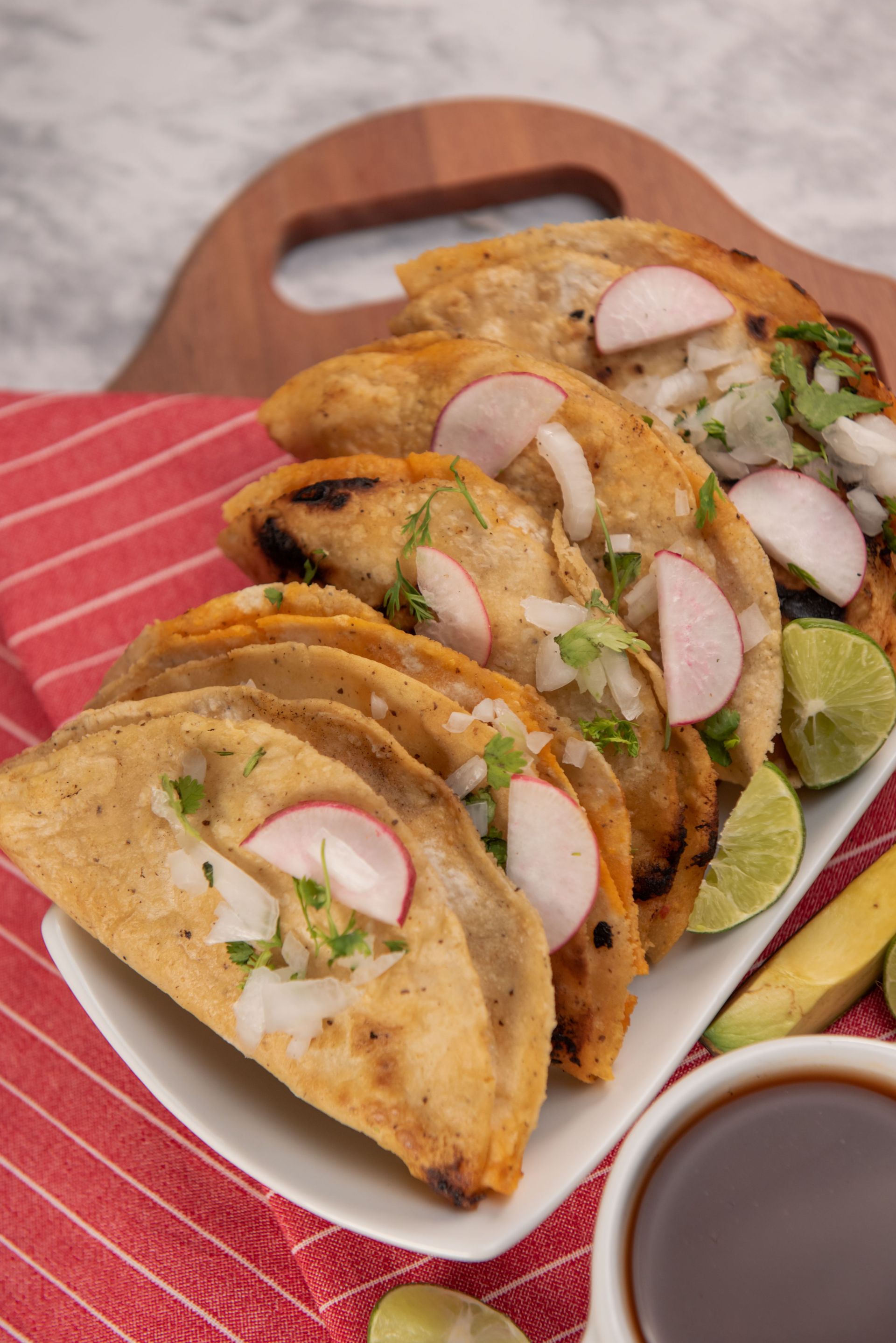 Traditional Mexican tacos served on a plate with fresh garnishes. Perfect for authentic cuisine enthusiasts.