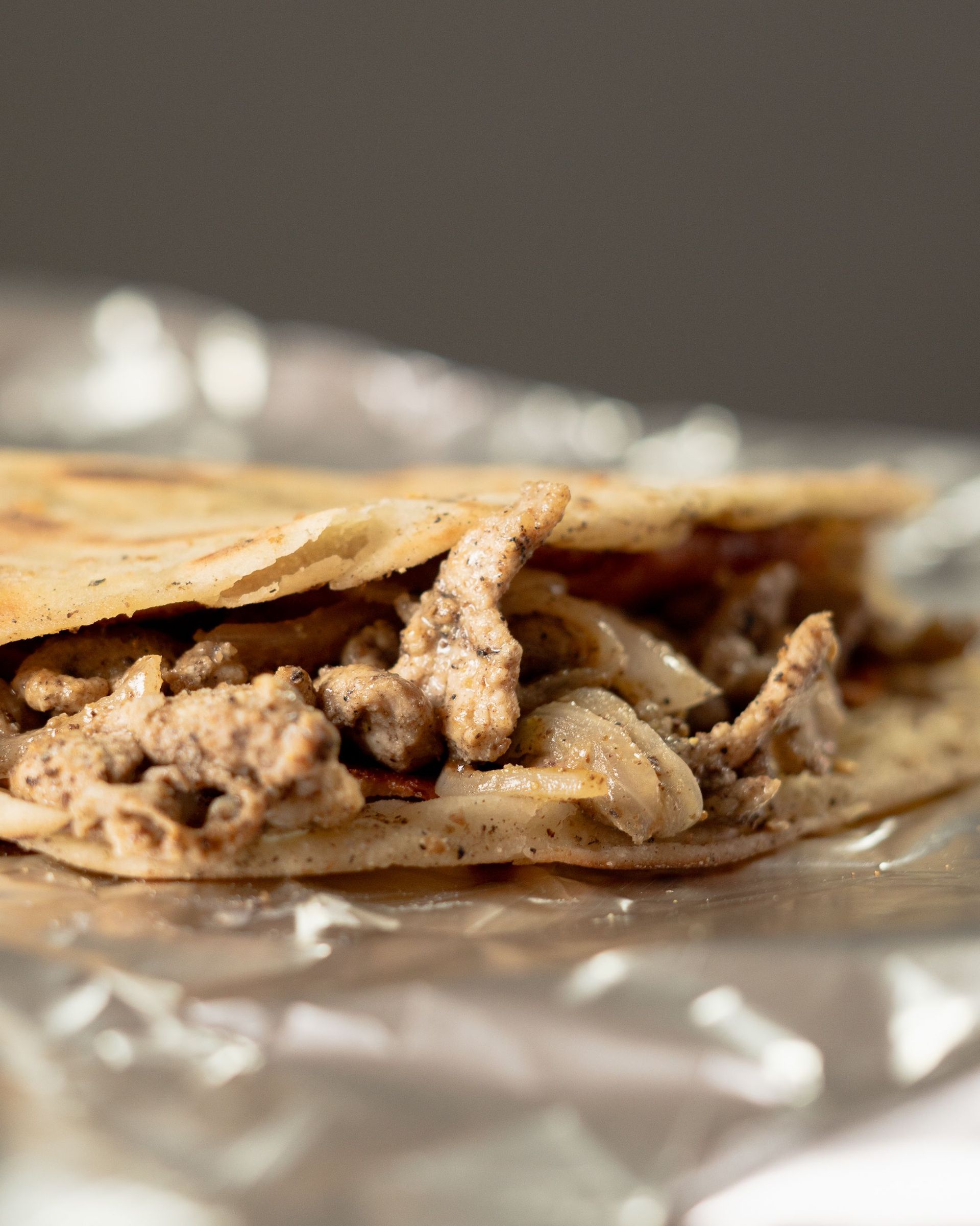 Close-up of a Lebanese meat pie with seasoned filling on foil.